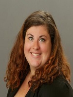 Woman posing for a professional photo smiling at the camera with long chestnut colored hair